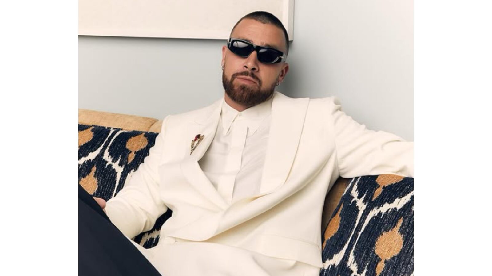 Travis Kelce wearing a white suite-jacket with black trousers.