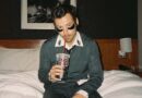 Harry Styles sitting on a bed.